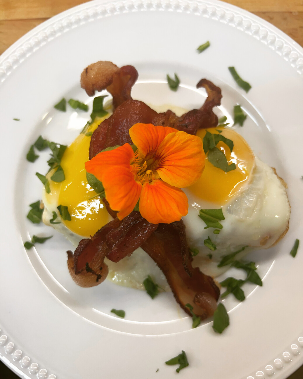 gormet breakfast with eggs and bacon and a flower garnish